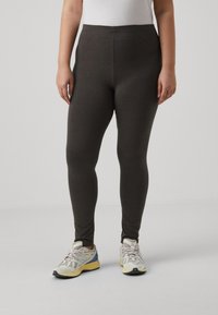 Dark gray leggings made of soft fabric, featuring a high waist and a fitted design, paired with light-colored athletic shoes.