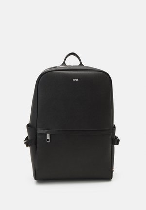 Black backpack with a textured surface, rectangular shape, top handle, side pockets, and a silver logo centered on the front panel.