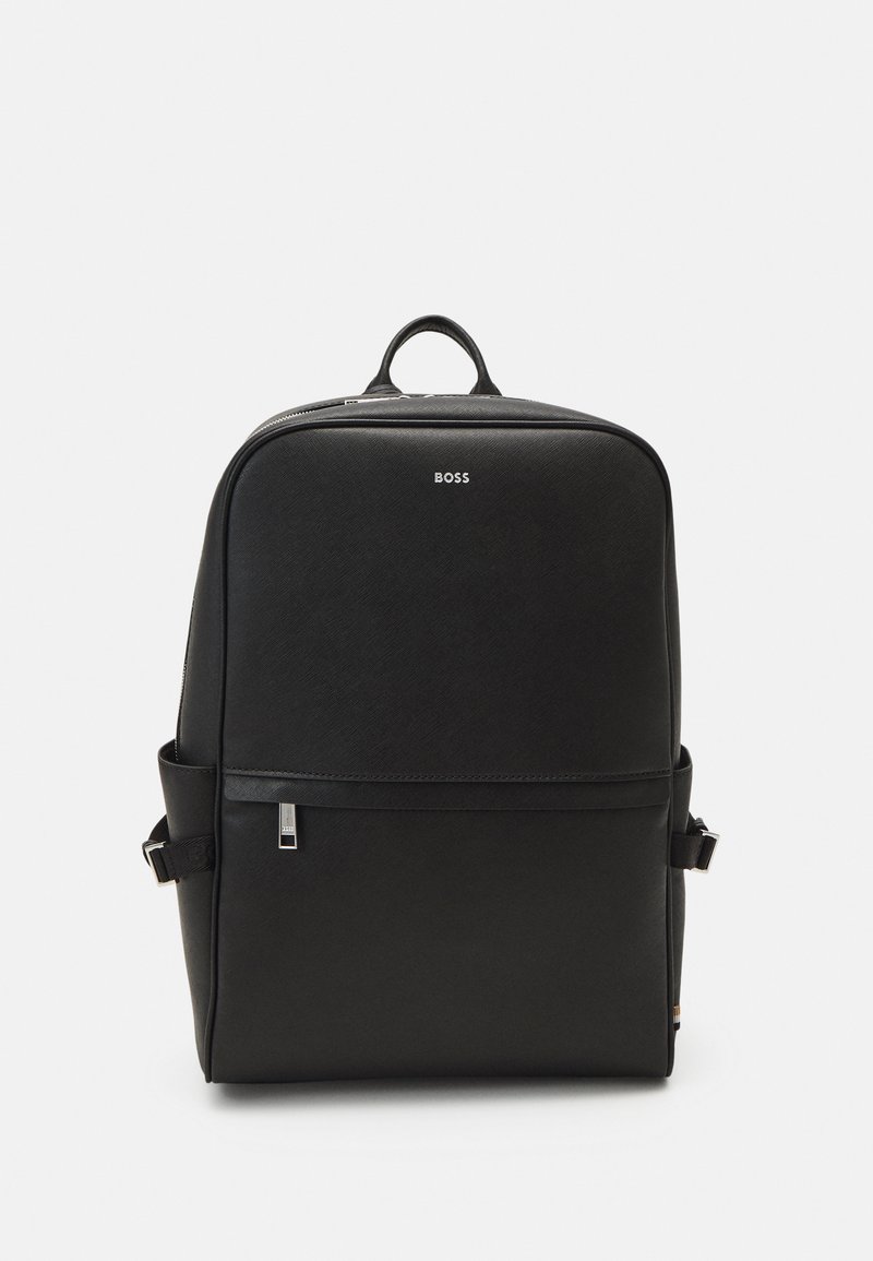 Black backpack with a textured surface, rectangular shape, top handle, side pockets, and a silver logo centered on the front panel.