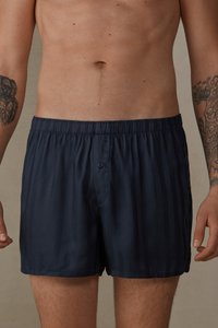 Shorts de bain bleu marine en tissu doux, avec un motif rayé, une taille élastique et une fermeture à bouton à l'avant.