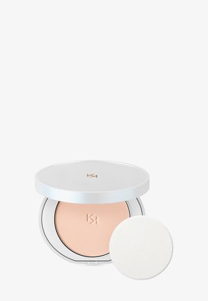 Compact powder makeup with a white round case, beige powder inside, and a separate white applicator sponge.