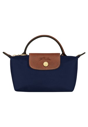 Marineblå lille håndtaske med brun læderklap og håndtag, guldknaplukning og lynlås på toppen.
