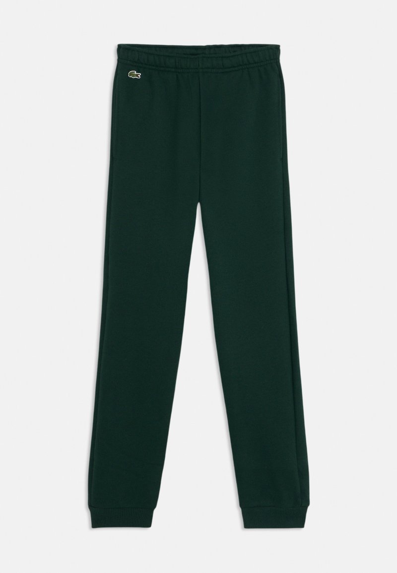 Tumši zaļi, kokvilnas sporta bikses ar elastīgu jostu un ribotām piedurknēm. Uz kreisās puses atrodas mazs Lacoste logo.