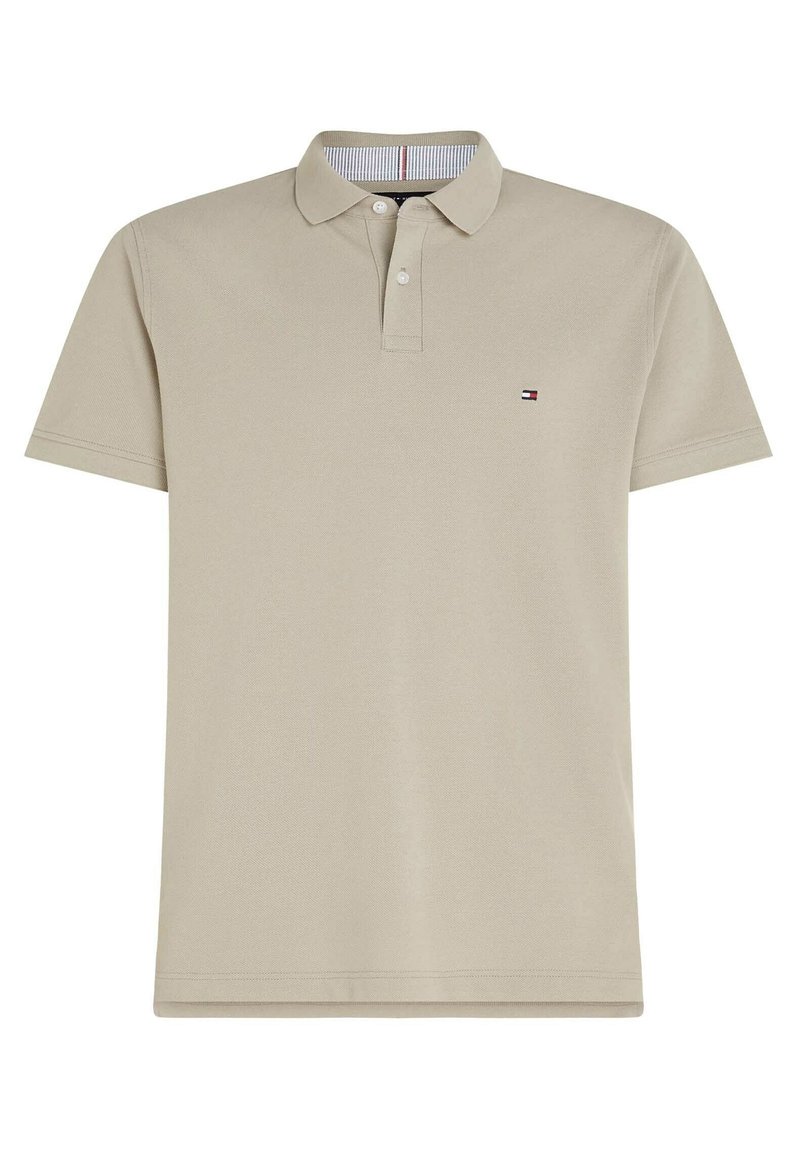 Polo beige à manches courtes avec col, deux boutons et un petit logo de drapeau rouge, blanc et bleu sur la poitrine gauche.