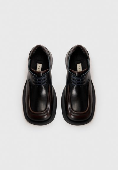 Čierne kožené šnurovacie topánky s okrúhlymi štvorcovými špičkami, textúrovaným povrchom, kontrastnými hnedými akcentmi a modrými očkami. Robustné gumové podrážky.