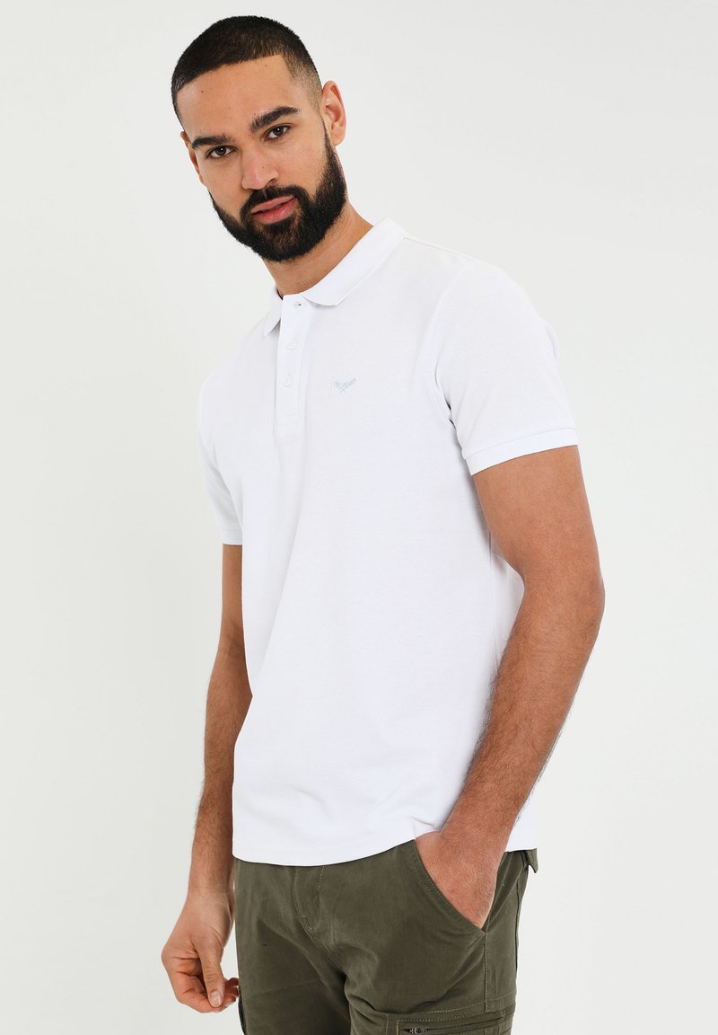 Hvid polo-shirt med en slim fit, korte ærmer og et diskret broderet logo på venstre bryst. Glat bomuldsstof med et klassisk design.
