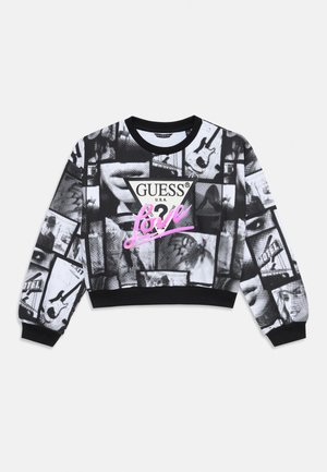 Černá zkrácená mikina s kolážovými monochromatickými obrázky, uprostřed bílý trojúhelník s nápisem "GUESS®" v černé barvě a "Love" napsané růžovým písmem.