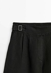 Zwarte linnen broek met hoge taille, voorzien van een gespdetail aan de voorkant, plooien en zijzakken; gladde textuur met een lichte glans.