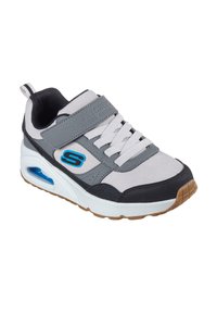 Zapatilla gris y blanca con una parte superior de cuero y malla, cierre de cordones y velcro, logotipo de acento azul y amortiguación de aire visible en la suela.