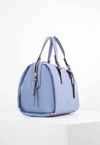 Jasnoniebieska torebka o zaokrąglonym kształcie, gładkiej fakturze, podwójnych uchwytach u góry, suwakach w kolorze srebrnym i brązowych akcentach.