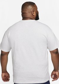 Vit kortärmad t-shirt i mjukt material, med en klassisk rund halsringning och avslappnad passform, samt synliga sömdetaljer på axlarna.