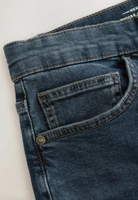 Dark blue denim jeans featuring a classic five-pocket design, visible stitching, and a metal button on the front pocket.