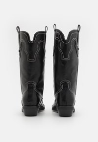 Zwarte leren cowboylaarzen met een geschulpt bovenstuk, witte stiksels en een korte blokhak. Voorzien van trekflappen aan beide zijden.