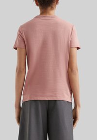 Korte mouw, zachtroze katoenen T-shirt met een ronde hals, een ontspannen pasvorm en een subtiele textuur, gecombineerd met grijze, losse broek.