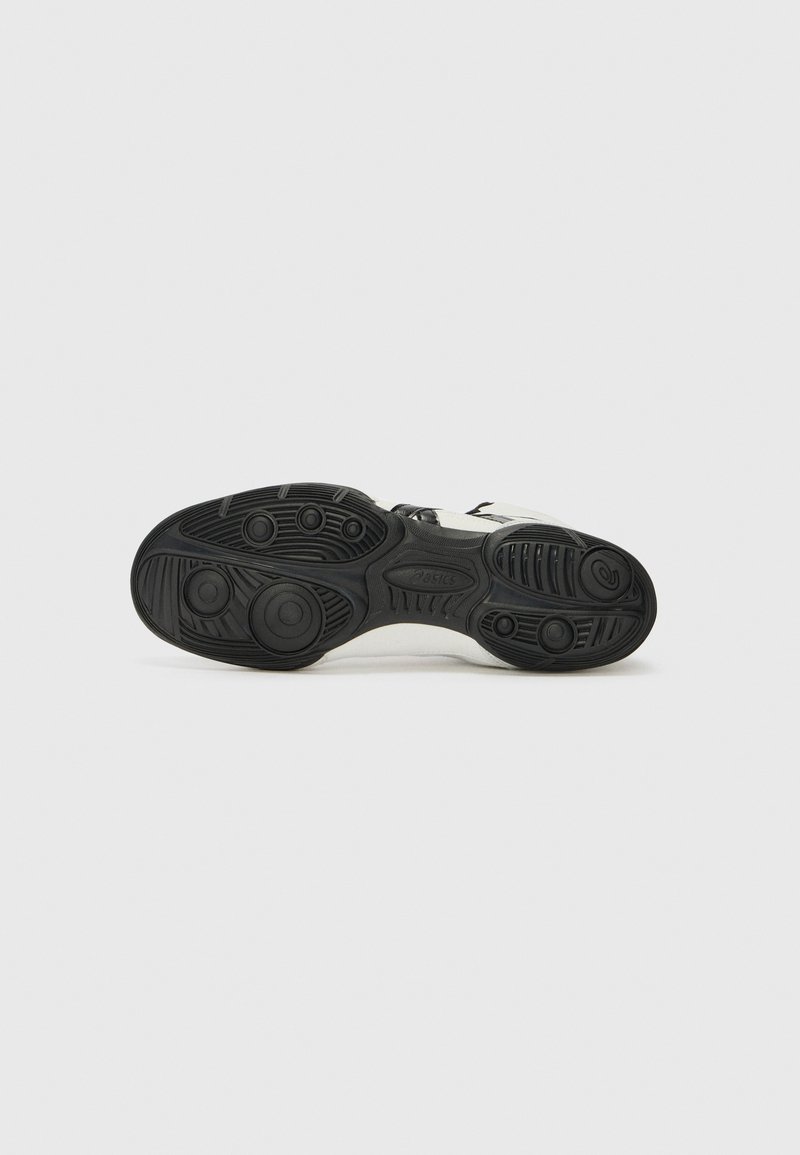 Sneaker with a black rubber outsole, textured grip patterns, and white midsole. Features a minimalist design with black accents.
