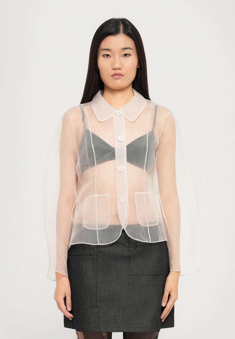 Kergest, heledast roosast värvi jakk, millel on krae, nööbid ees ja kaks eesmist taskut. Pikad, puhvitatud varrukad lisavad tekstuuri ja detaile.