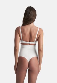 Witte high-waisted zwempak met dunne verstelbare bandjes en een haaksluiting achter. Glad textuur en strak ontwerp.