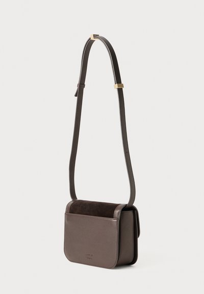Rjavo usnjeno in semiš crossbody torbico z rectangularno obliko, nastavljivim trakom in diskretno oznako na sprednji strani. Gladka textura.