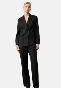 Sort nålestribet jakkesæt med en dobbeltradet blazer med to knapper og lige bukser; slank, skræddersyet pasform med lomme detaljer.