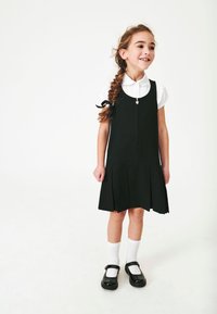 Rochie neagră fără mâneci, cu fustă plisată, guler alb și fermoar cu inimă argintie. Asortată cu șosete albe cu dantelă și pantofi negri.