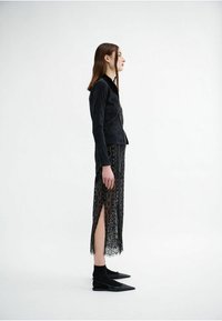 Black corduroy jacket with a zipper, paired with a black lace skirt featuring cutouts and side slits. Styled with black pointed flats.