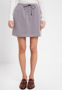 Gestreepte minirok in zwart en wit met een elastische tailleband en trekkoord. Draag het met bruin leren loafers.