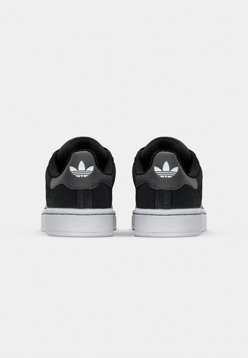 Sneaker in suede nero con suola in gomma bianca, dotati di una linguetta sul tallone nera lucida e di un piccolo logo bianco sul retro.