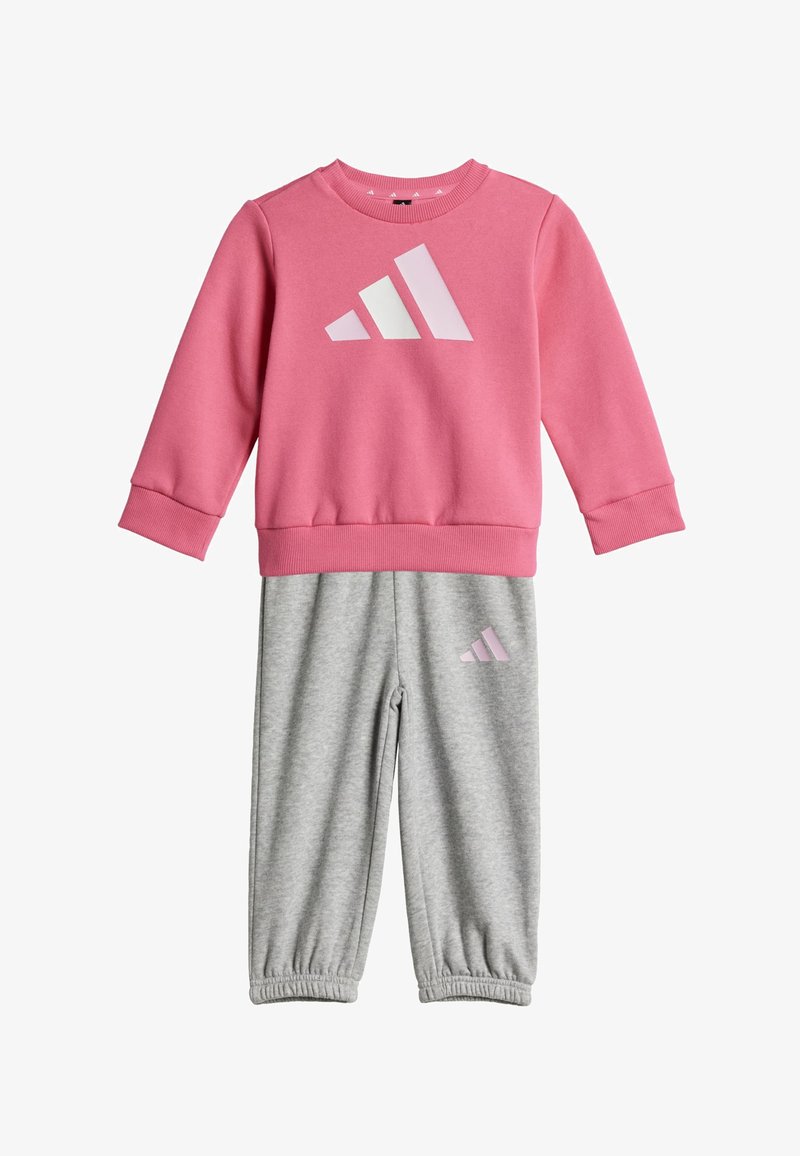 Sweat-shirt à manches longues rose avec logo blanc et rose clair, associé à un pantalon de survêtement gris clair avec ourlet élastique et petit logo assorti.