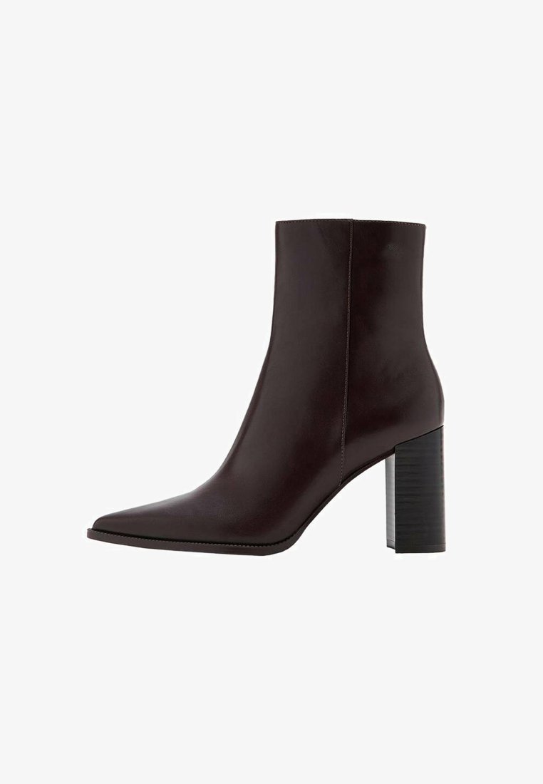 Botte de cheville en cuir marron avec un bout pointu, un talon bloc haut et une texture lisse. Présente des coutures minimales et un design épuré.