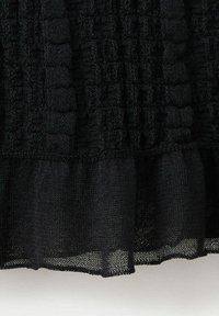 Tissu tricoté noir présentant des côtes verticales texturées au-dessus d'un ourlet froncé transparent et tissé de façon lâche.