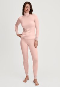 Roze geribbelde thermoshirt met een col, gecombineerd met bijpassende legging. Kantaccenten bij de manchetten en enkels. Zacht, aansluitend ontwerp.