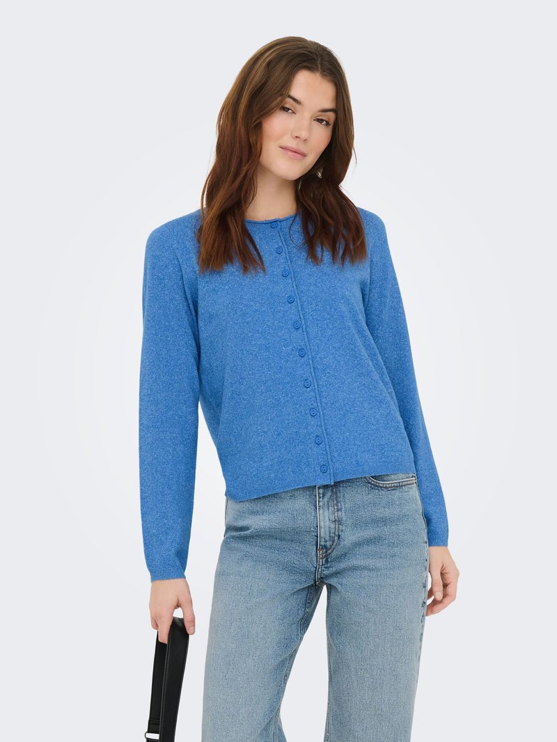 Cardigan bleu tricoté avec col rond, manches longues et fermeture à boutons sur le devant. Associé à un jean taille haute bleu clair.
