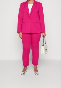 Fuchsia kavaj och matchande byxor i strukturerad tyg. Inkluderar en vit topp och silverfärgade ballerina, samt en liten vit handväska.