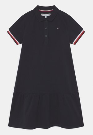 Navy-Polo-Kleid mit kurzen Ärmeln, weißen und roten gestreiften Akzenten, einer Knopfleiste und einem gerafften, gestuften Rock. Hergestellt aus weichem Baumwollmaterial.