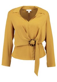 Blusa a maniche lunghe giallo senape con scollatura a V profonda, collo e un nastro avvolgente fissato da una fibbia circolare in acetato tartarugato.