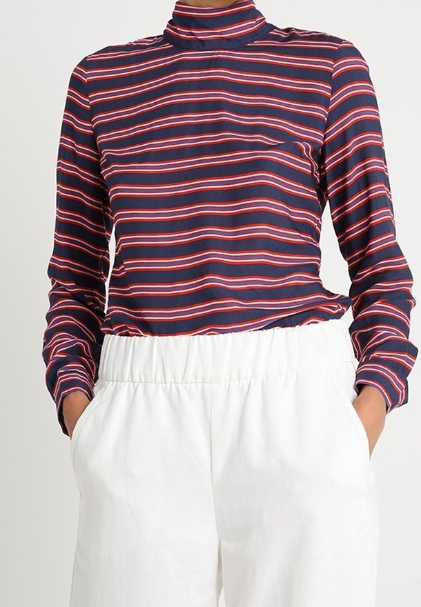 Maglia a righe blu navy e rossa a maniche lunghe con scollo alto, realizzata in tessuto morbido, abbinata a pantaloni bianchi con vita elasticizzata.