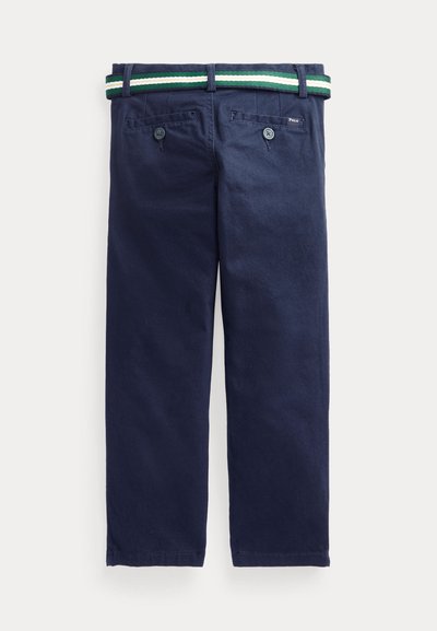 Pantalones azul marino con dos bolsillos traseros con botones y un cinturón a rayas verde, blanco y azul marino pasado por las trabillas.
