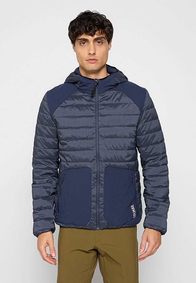 Veste matelassée marine avec capuche, dotée de lignes de couture horizontales, de deux poches avant et de panneaux d'épaule contrastés. Matériau léger.