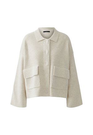 Afgeknot beige gebreid shirt met een kraag, knoopsluiting en twee grote voorzakken. Zachte textuur, brede mouwen en een relaxte pasvorm.