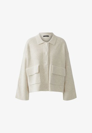 Beige gestricktes Oberteil in Cropped-Form mit einem Kragen, Knopfverschluss und zwei großen Fronttaschen. Weicher Griff, weite Ärmel und lockere Passform.