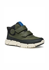 Zapato infantil verde y negro con dos correas de Velcro, un parche de logo azul, suela de goma texturizada y un cuello acolchado para mayor soporte.