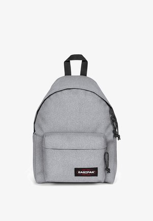 Šedý textilní batoh s kulatým vrškem, přední kapsou a černými kovovými prvky. Obsahuje nastavitelná ramenní popruhy a nášivku s logem na dolní části předního panelu.