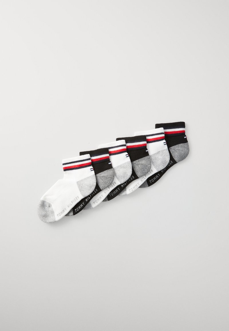 Sześć par skarpetek bawełnianych w kolorach białym, szarym i czarnym, z paskowanymi mankietami i logo na podeszwach. Każda para ma inną kombinację kolorystyczną.