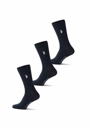 Trois chaussettes noires montantes avec le logo blanc U.S. Polo Assn. près du haut et le nom de la marque sur la voûte plantaire.