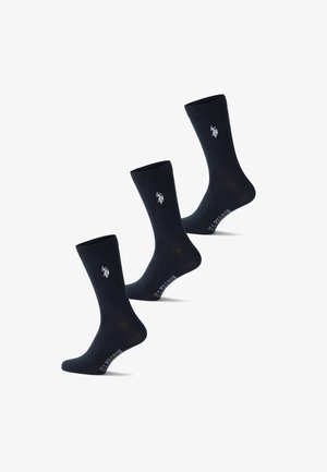 Trois chaussettes noires montantes avec le logo blanc U.S. Polo Assn. près du haut et le nom de la marque sur la voûte plantaire.