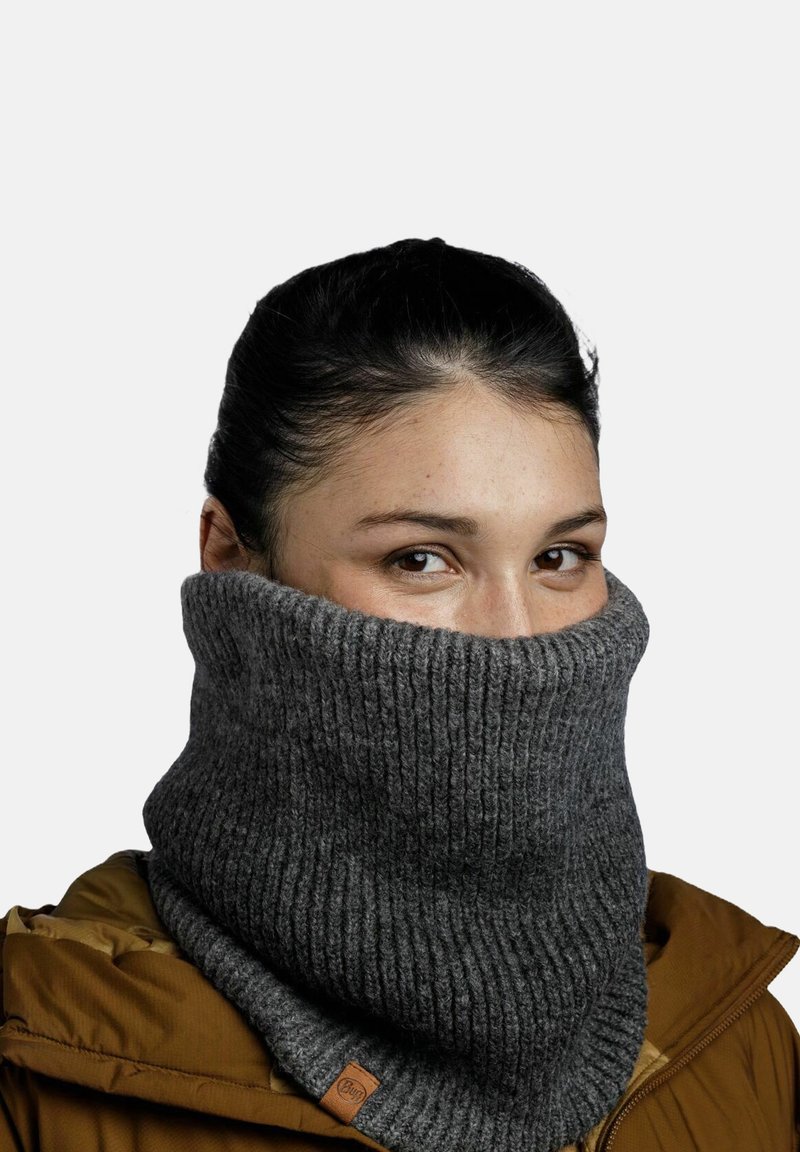 Knit gray neck warmer with a ribbed texture, featuring a folded design and a small leather accent. Worn over an olive-brown jacket.