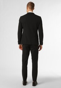 Zwarte suit met een strak ontwerp, zachte textuur en slim fit. Bevat een enkele split aan de achterkant en stijlvolle mouwdetails.