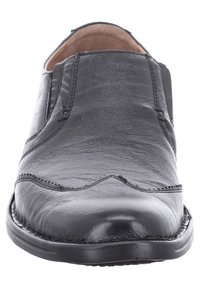 Černé kožené nazouvací boty s hladkou texturou, kulatou špičkou, kontrastním vyšíváním a raženými detaily na přední části. Plochá podrážka.