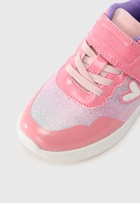 Ροζ αθλητικό παπούτσι με γκλίτερ φινίρισμα, που διαθέτει λαμπερό ροζ καπάκι στο μπροστινό μέρος, μοβ εσωτερική επένδυση και υφασμένες κορδόνια. Περιλαμβάνει λουράκι με βέλκρο.