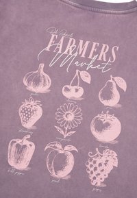 Chemise violette avec des croquis roses et des étiquettes d'ail, cerises, poire, fraise, fleur de marguerite, tomate, poivron, pêche et raisins.